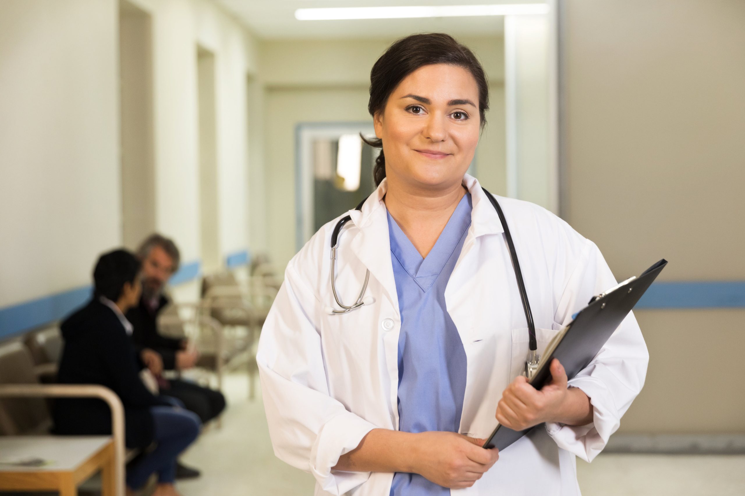 a doctor smiles while holding her clipboard scaled